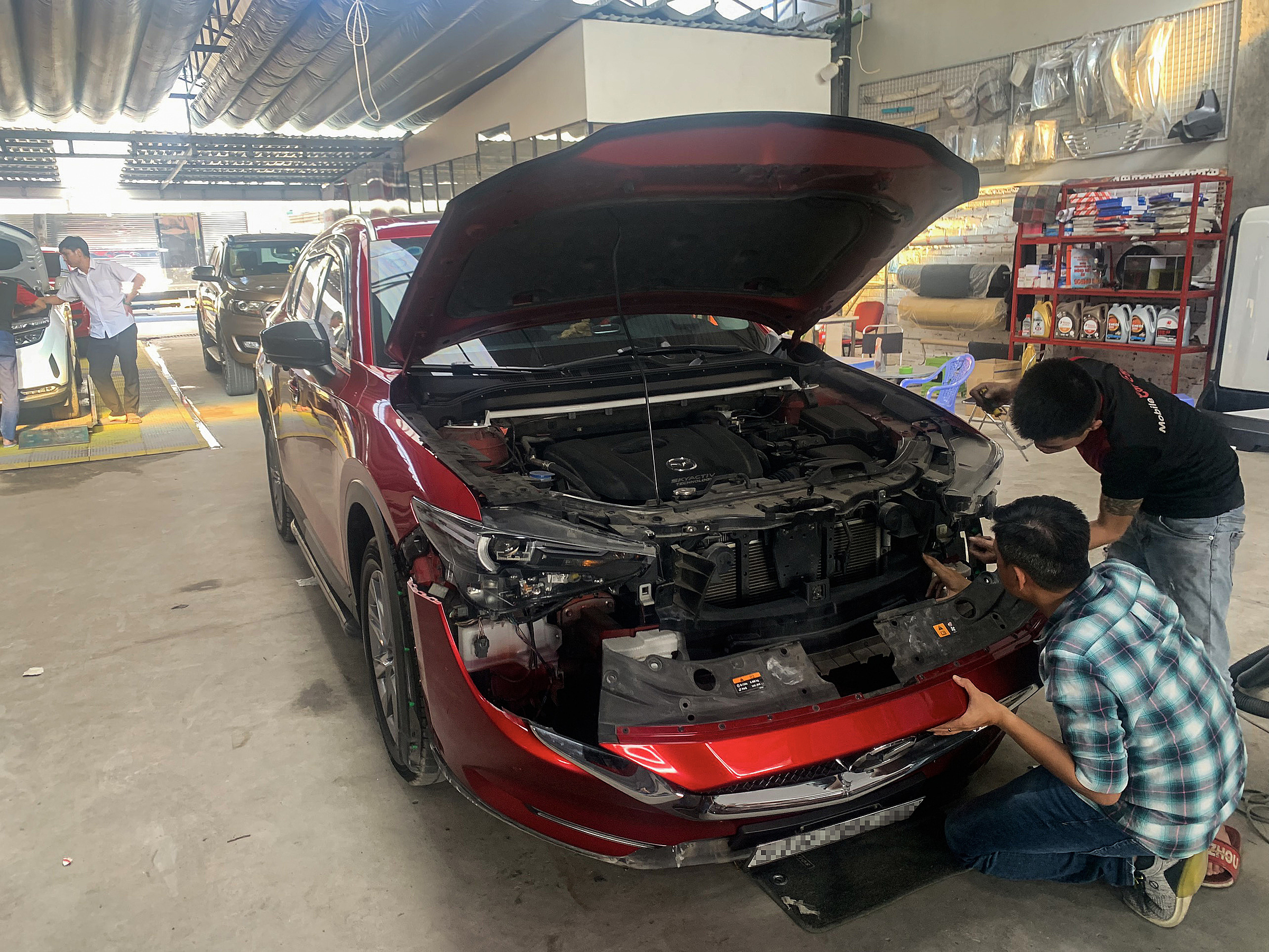 Chiếc Mazda CX-5 được tháo mặt ca-lăng để lắp lại đèn zin trước khi đi đăng kiểm, tại một garage ở quận 12. Ảnh: Phú Tống