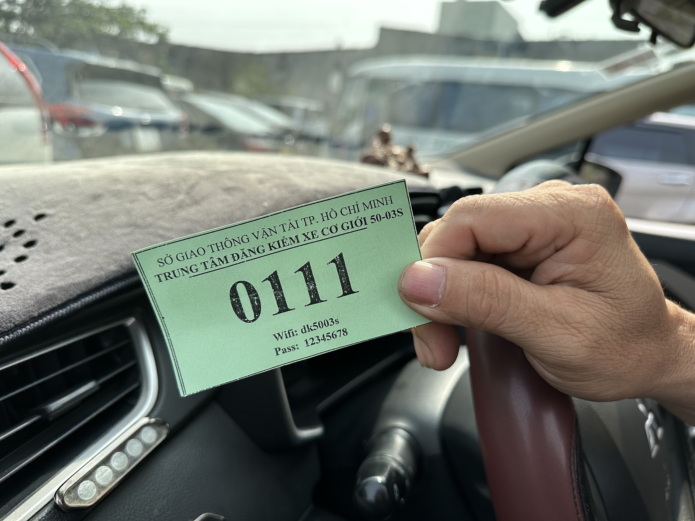 Một tài xế cầm số thứ tự 111 chờ vào đăng kiểm xe sau khi sắp hàng từ 4 giờ, ngày 27/12.